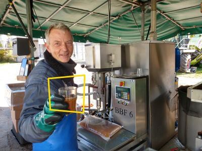 Mann reicht frisch gepressten Apfelsaft im Becher